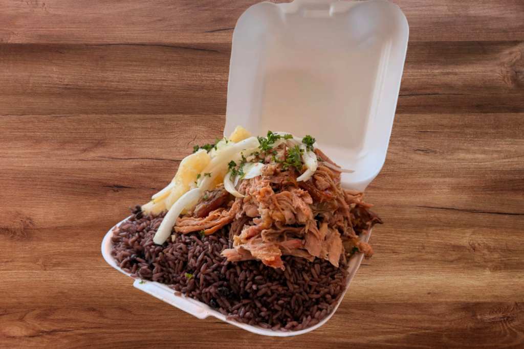 Arroz moro, vaca frita with white pickled onion, and yuca frita in styrofoam container to go.