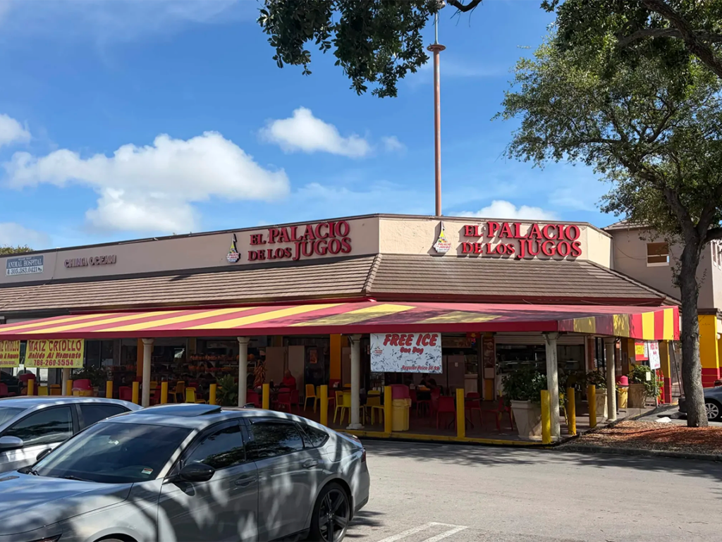 El Palacio de los Jugos corner location at Miller Drive. Beige walls, red lettering and its signature red and yellow awnings.