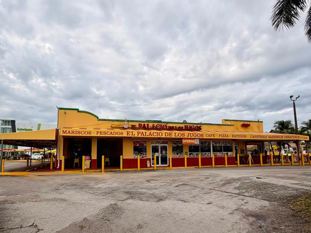 El Palacio de los Jugos at SW 8th St & 143rd Ave. Yellow building with red base and lettering. Large parking lot.
