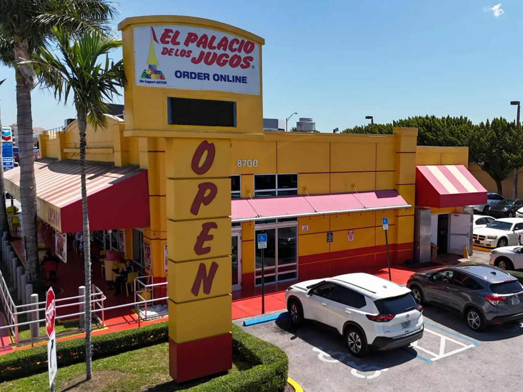 "OPEN" sign of El Palacio de los Jugos at SW 87th Ave & SW 8th St. Red lettering, yellow building, red awning.